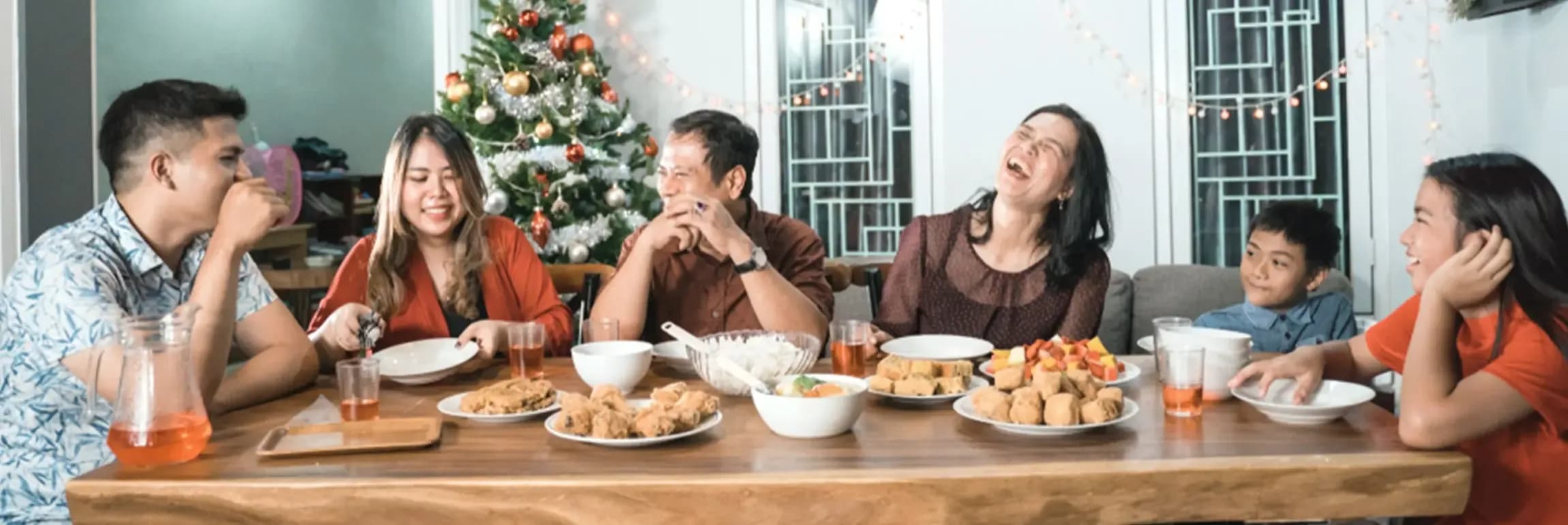 A family seated at the dining table happily eating and talking with one another